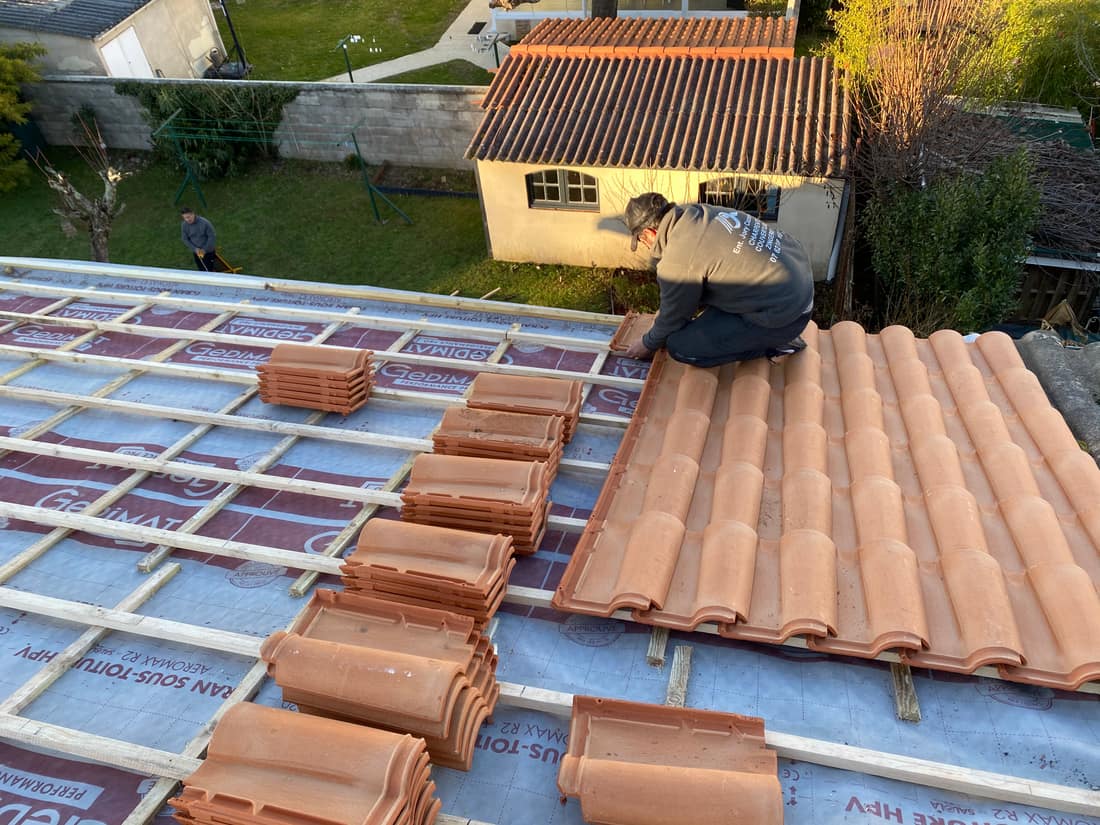 Artisan couvreur posant des tuiles neuves lors d'une rénovation de toiture